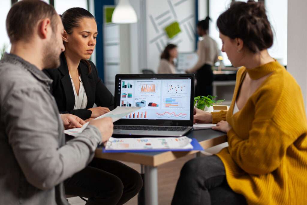 Ludzie siedzący przy laptopie, omawiający nowoczesny CRM wdrożony do firmy.